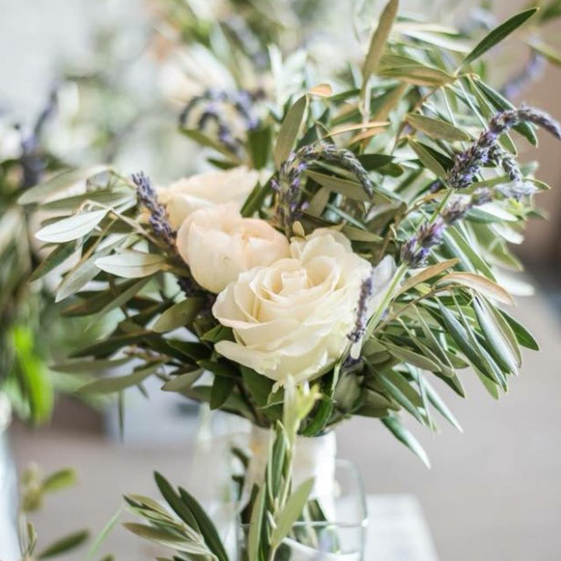 White roses with skinny green leaves displayed as a small bouquet in a glass vase