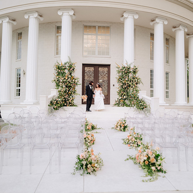 Front entrance of Whitehurst Gallery with bridal couple on steps with lots of flowers flanking the aisle