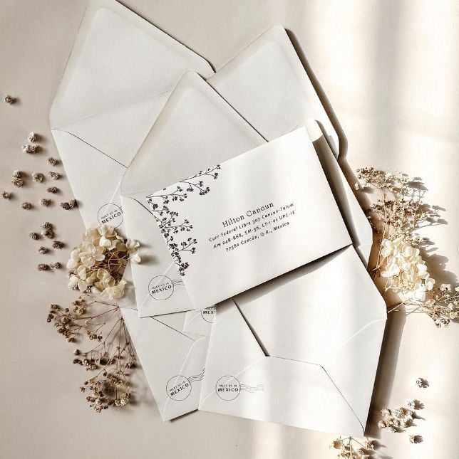 image of wedding stationary showing a wedding invitation, envelope, and reply card and reply envelope on a brown rustic background with pastel flower sprigs