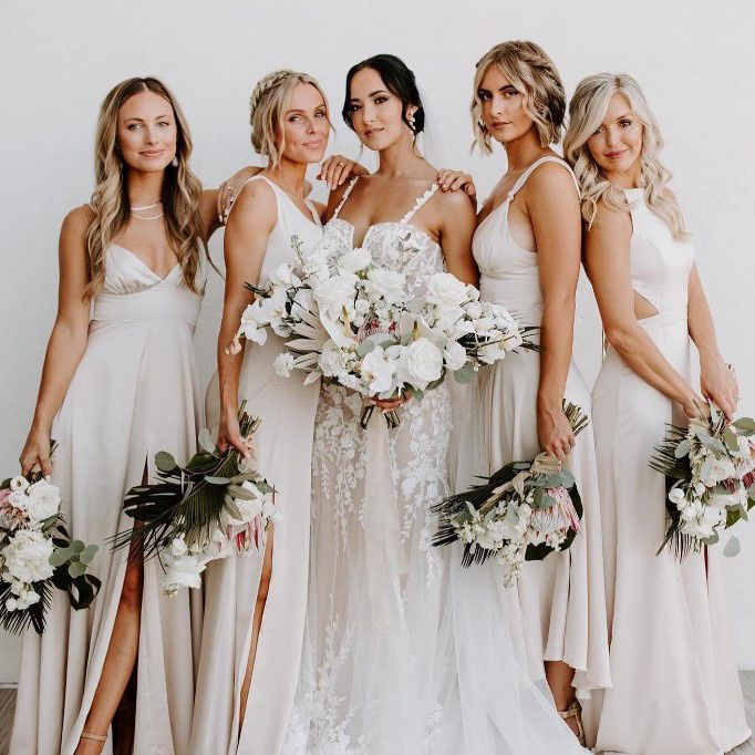 image a a bride with 4 bridesmaids in dusty pink dresses holding large bouquets with white and pale pink flowers and light green leaves with beautiful hair and makeup