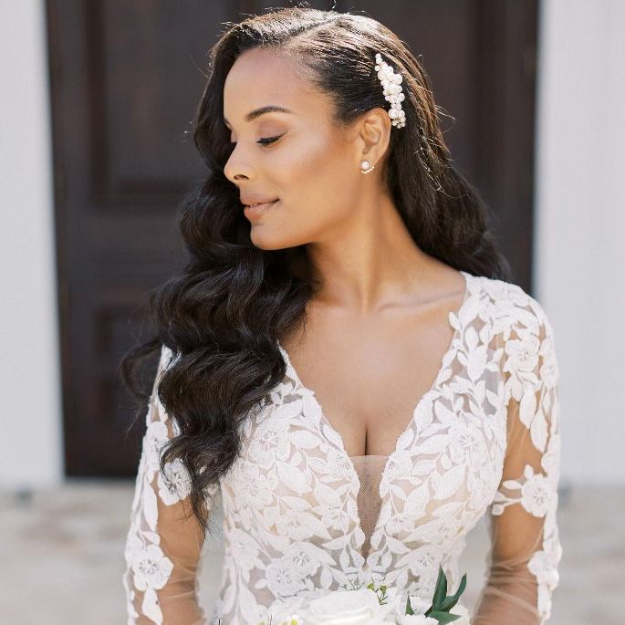 Image of a bride wearing an applique dressing with a deep v neckline with her har swept up to one side with a pearl comb