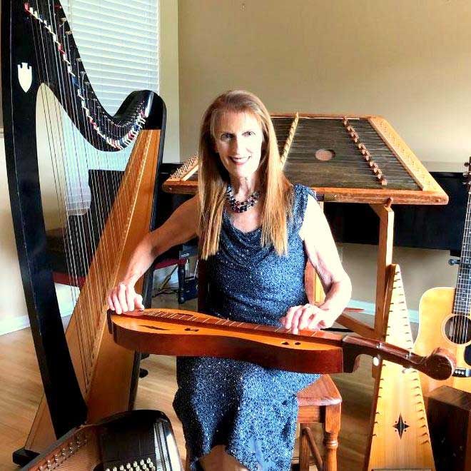 Bonnie Whitehurst sitting with her harp and other instruments
